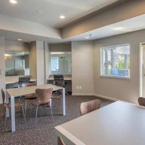 Community study lounge with tables, chairs, desks, and window at Sharps Flats in Davis