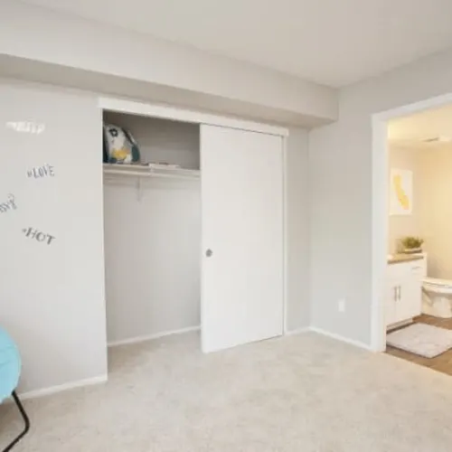Carpeted bedroom with sliding-door closet and adjoining bathroom visible