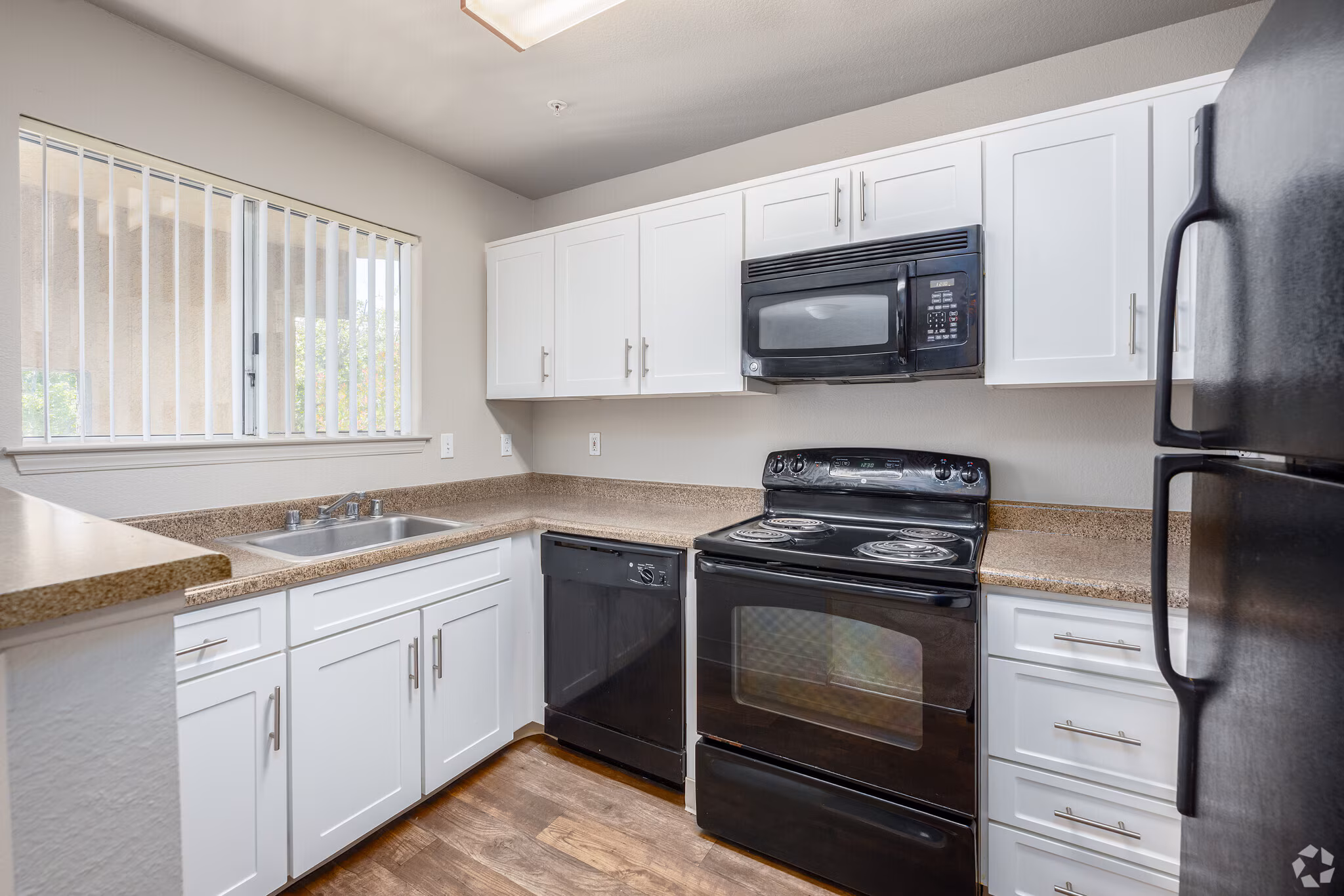 Modern apartment kitchen with white cabinets and stainless steel appliances