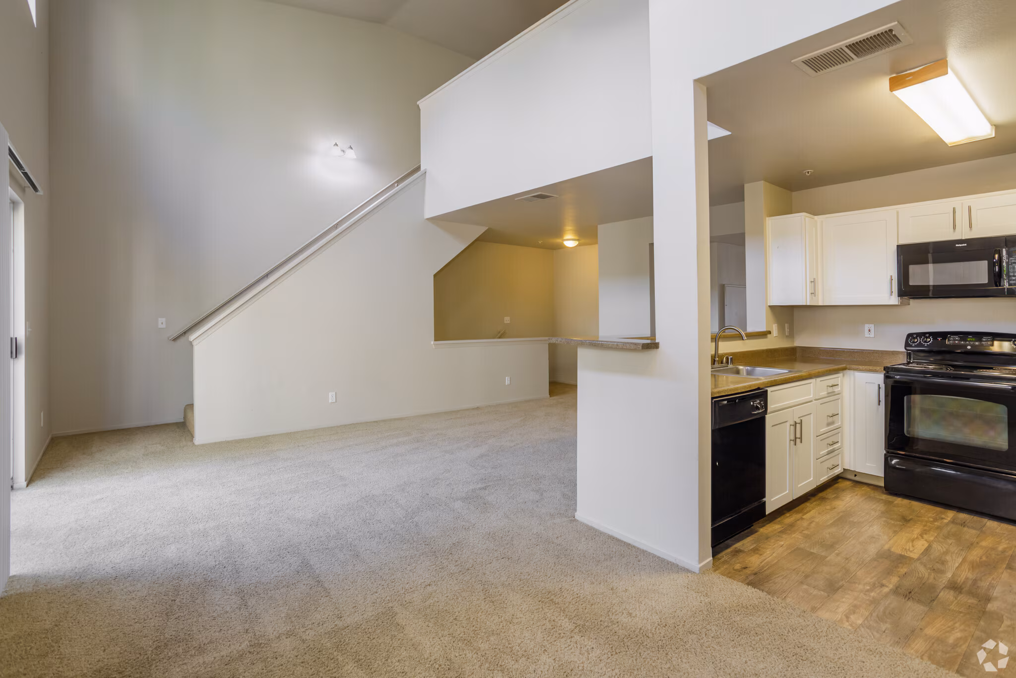 Bright apartment kitchen with light cabinetry and open living space