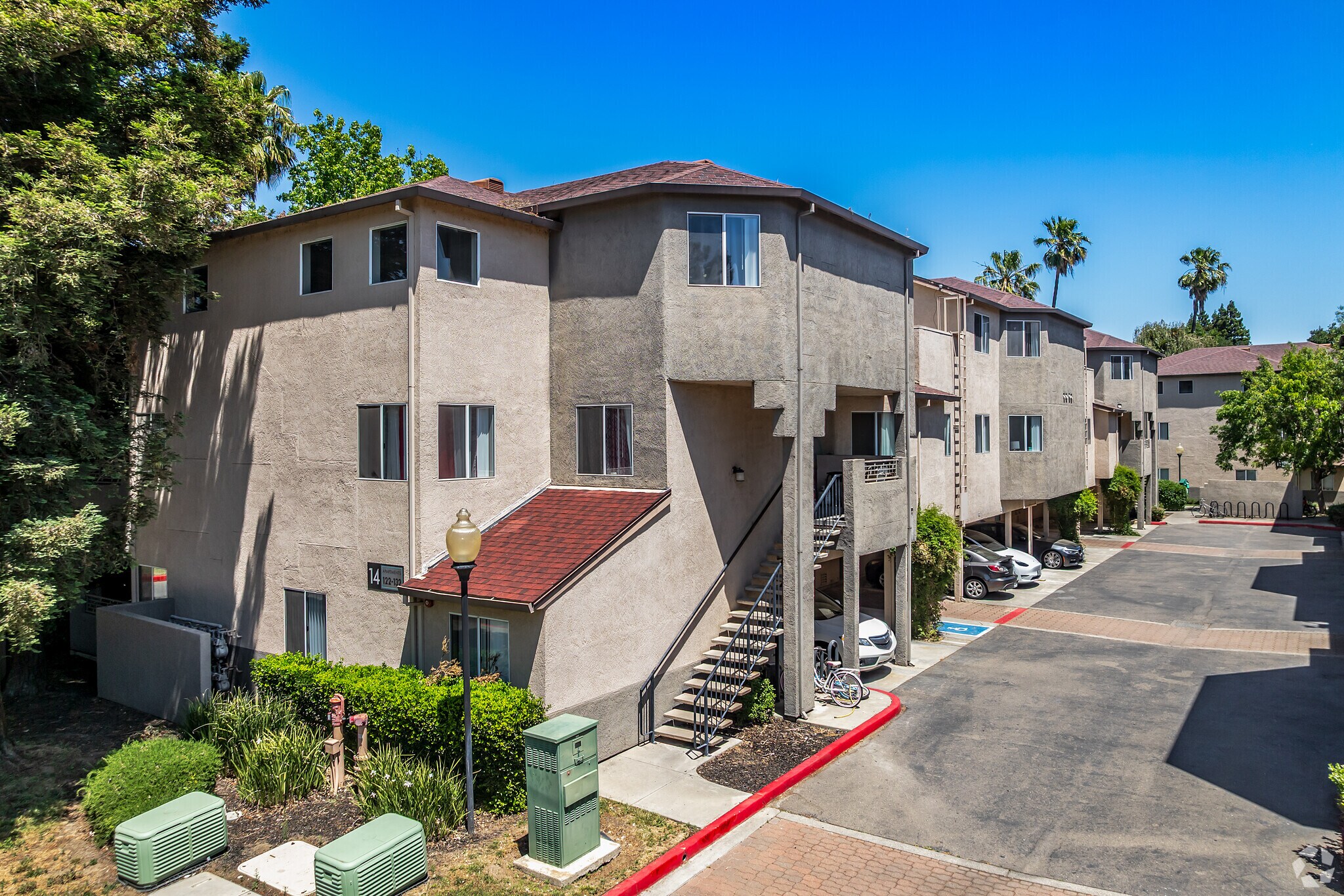 Exterior view of Sharps Flats apartment buildings, parking area, and palm trees in Davis, CA