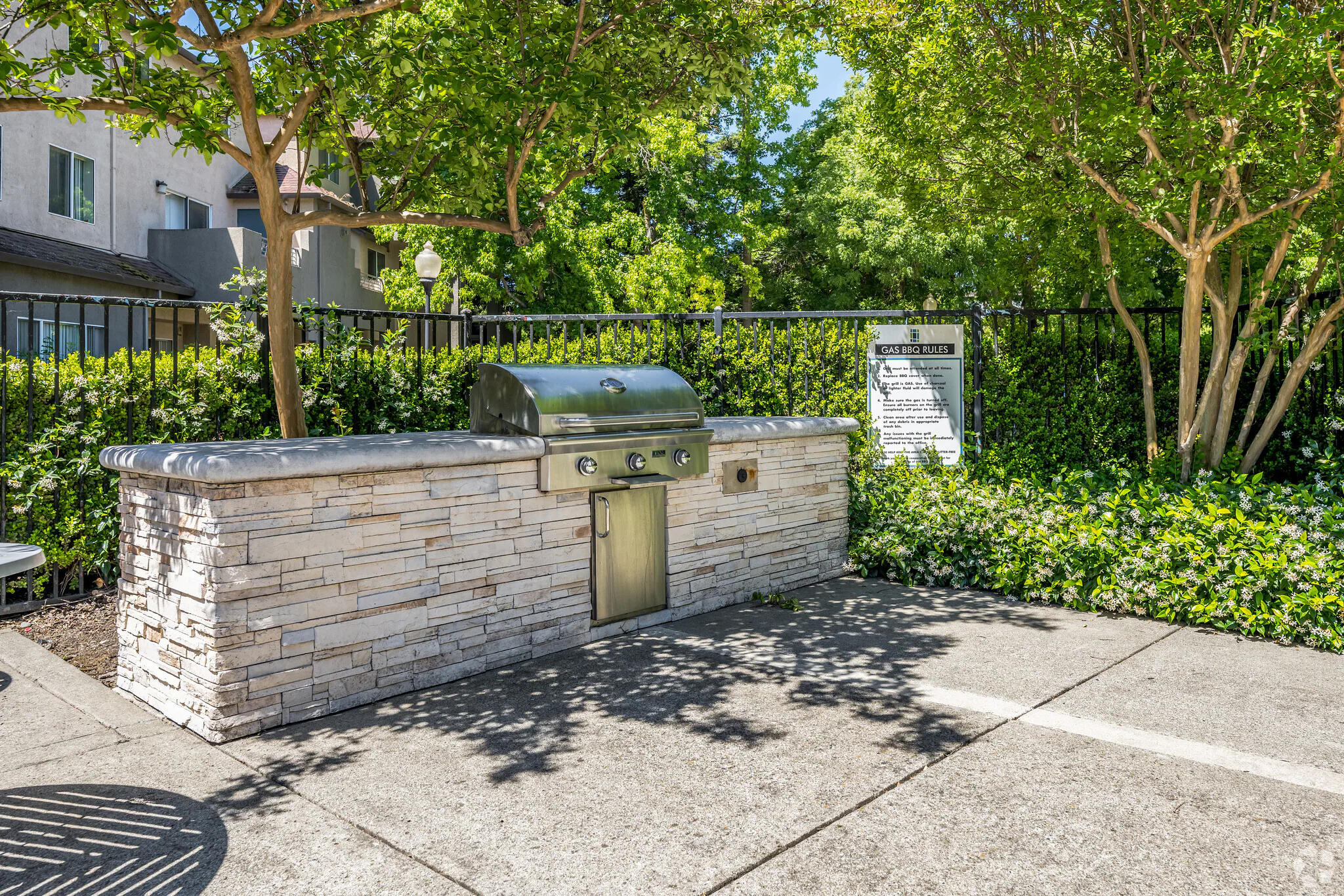 Outdoor gas BBQ with stone counter in a landscaped common area at Sharps Flats apartments