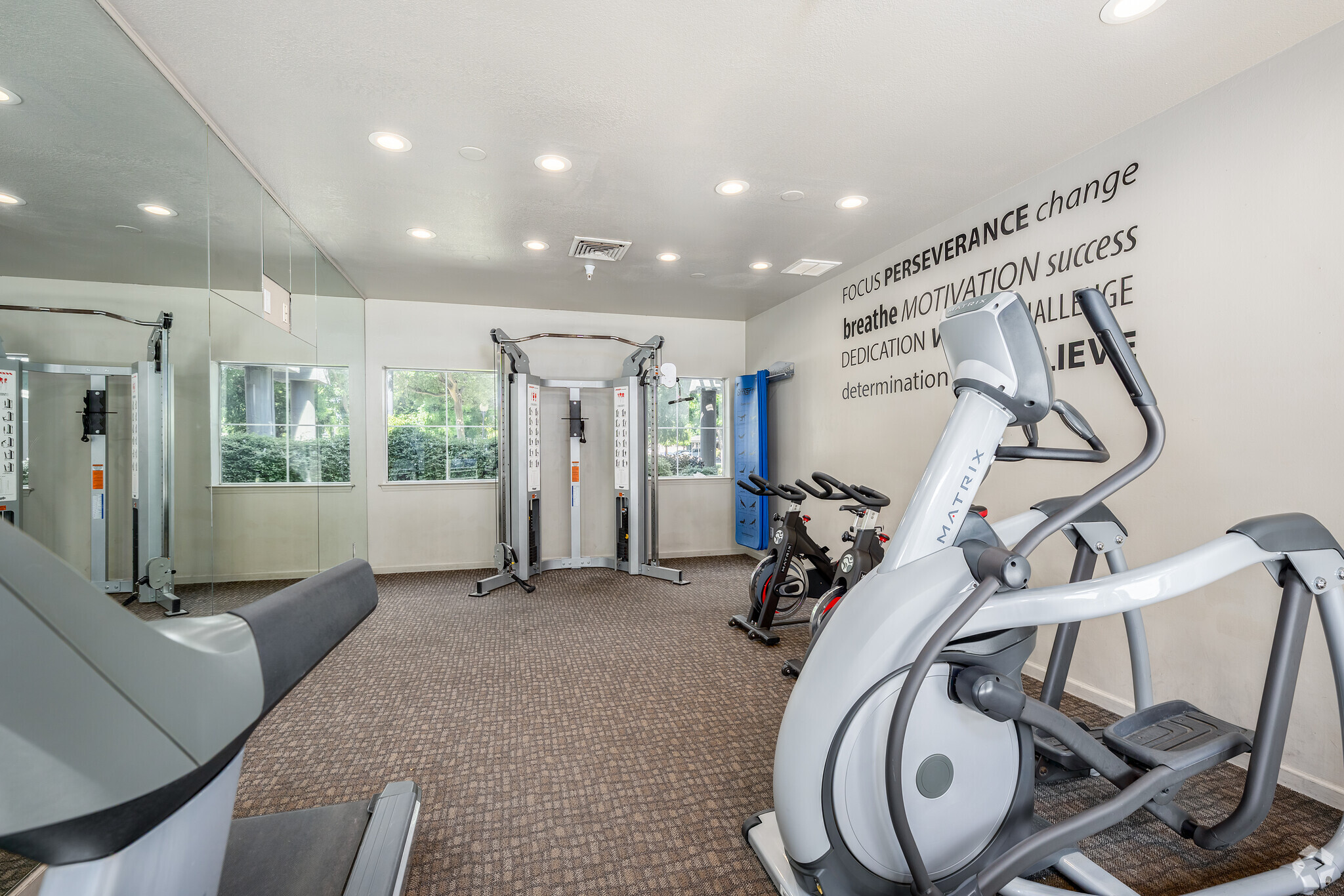Apartment fitness room with ellipticals, stationary bikes, weight machine and motivational wall text