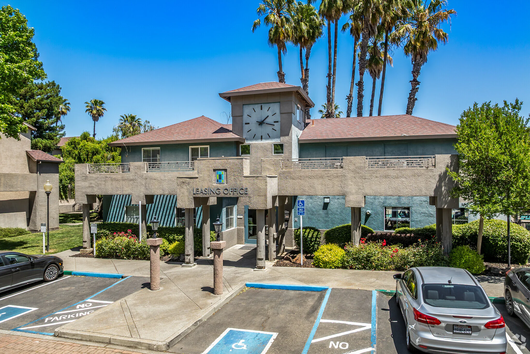 Leasing office entrance of student apartments with clock tower, palm trees, and accessible parking